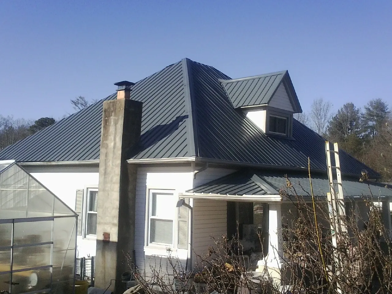 Dark blue standing seam metal roof on a white farmhouse with dormer — Slate & Tile Roof Repair by Roofing Brothers in Moshannon