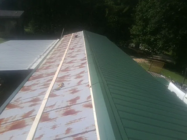 Old rusted panels beside newly installed green metal roofing — Wind Damage Roof Repair by Roofing Brothers in Moshannon