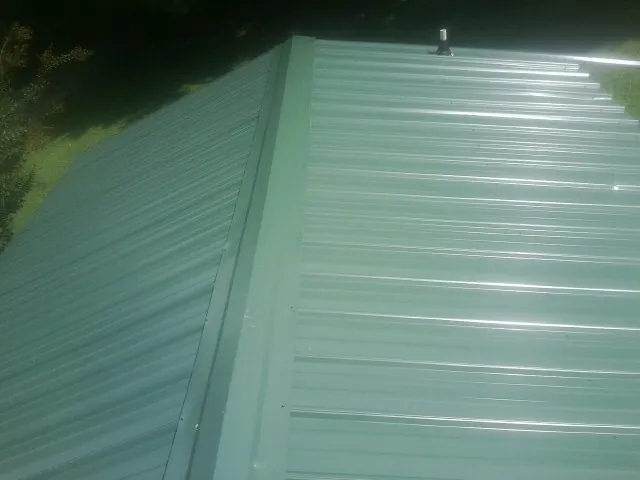 New green metal panels meeting at the ridge of a roof — Flat Roof Repair work by our crew in Moshannon