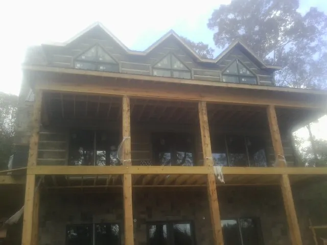 Dormers and porch framing on a large log home under construction — Roof Coating work by our crew in Moshannon