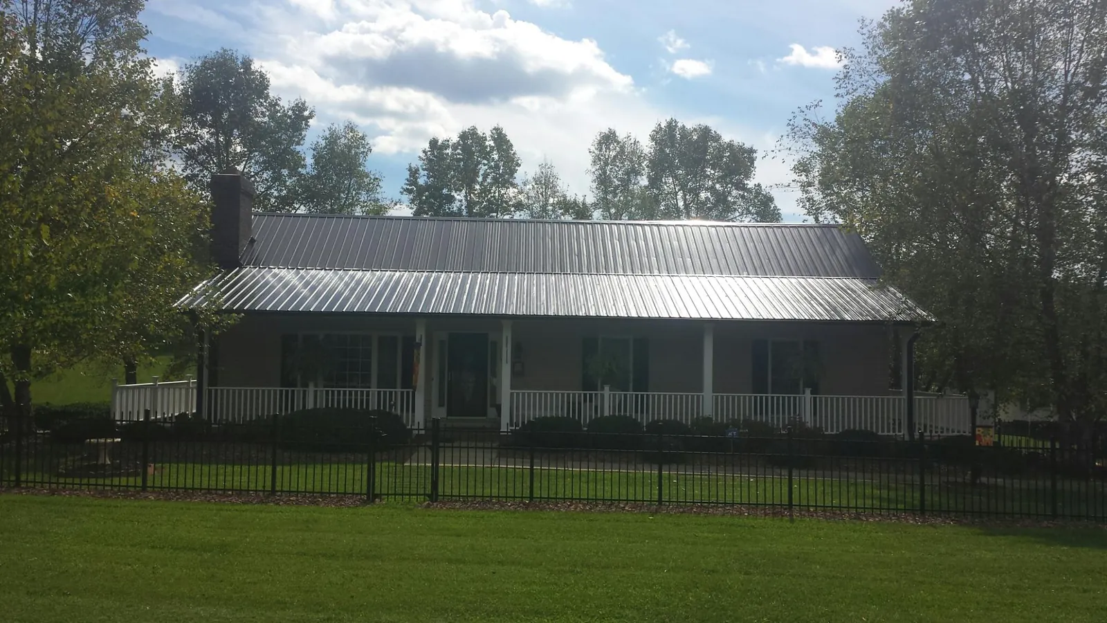 Gray metal roof on a brick ranch with a full width front porch — Gutter Guard Installation work by our crew in Moshannon