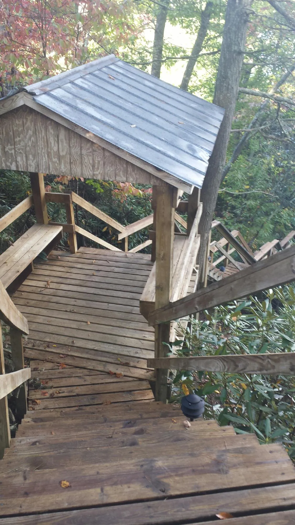 Metal roofed shelter over wooden steps on a wooded walkway — Skylight Repair & Installation work by our crew in Moshannon