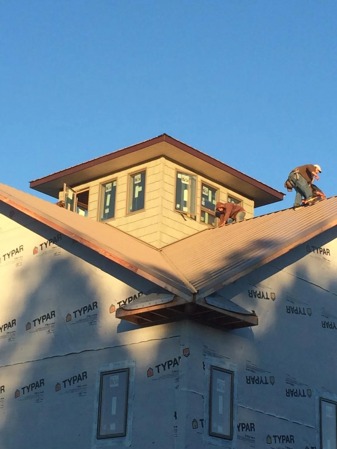 Roofers working around a rooftop cupola on a new metal roof at sunset — Roof Waterproofing in Moshannon by Roofing Brothers